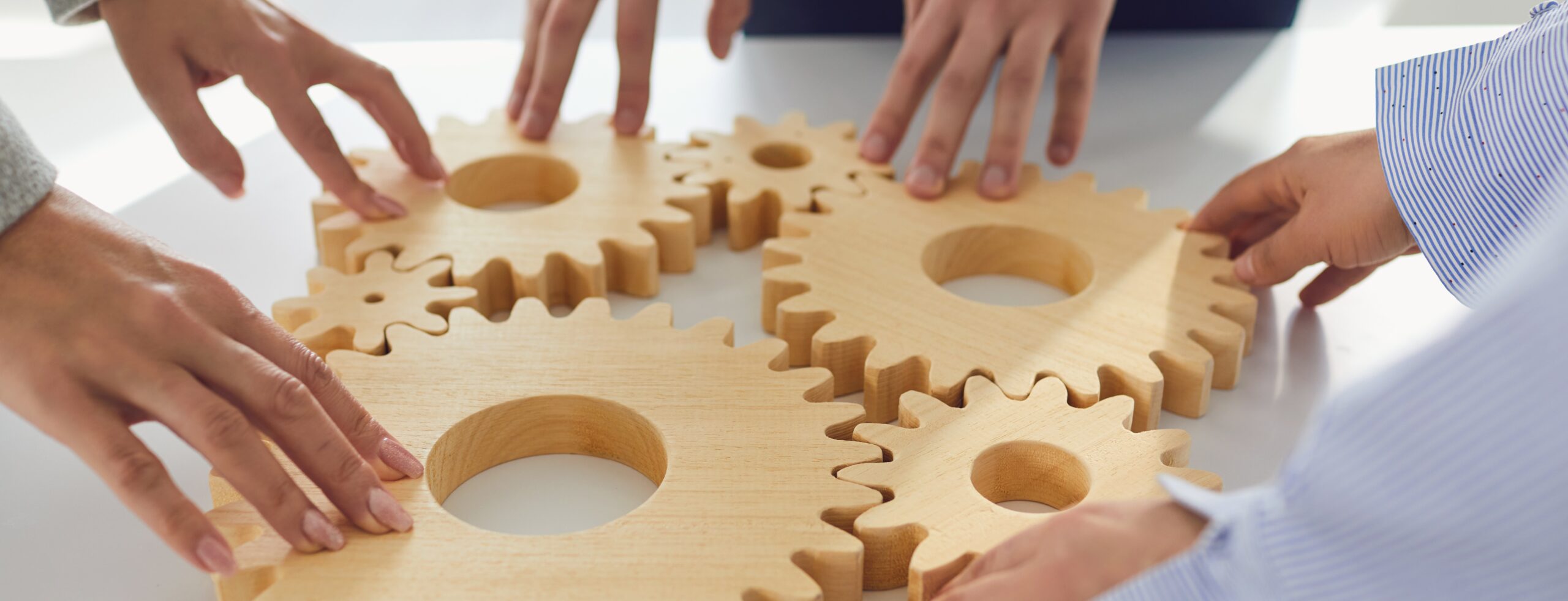 Crop business people stacking cogwheels in team